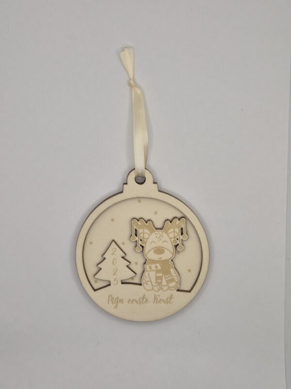 Detail houten kerstbal met rendier – mijn eerste kerst Close-up van houten kerstbal mijn eerste kerst met gravure rendier en jaartal 2026