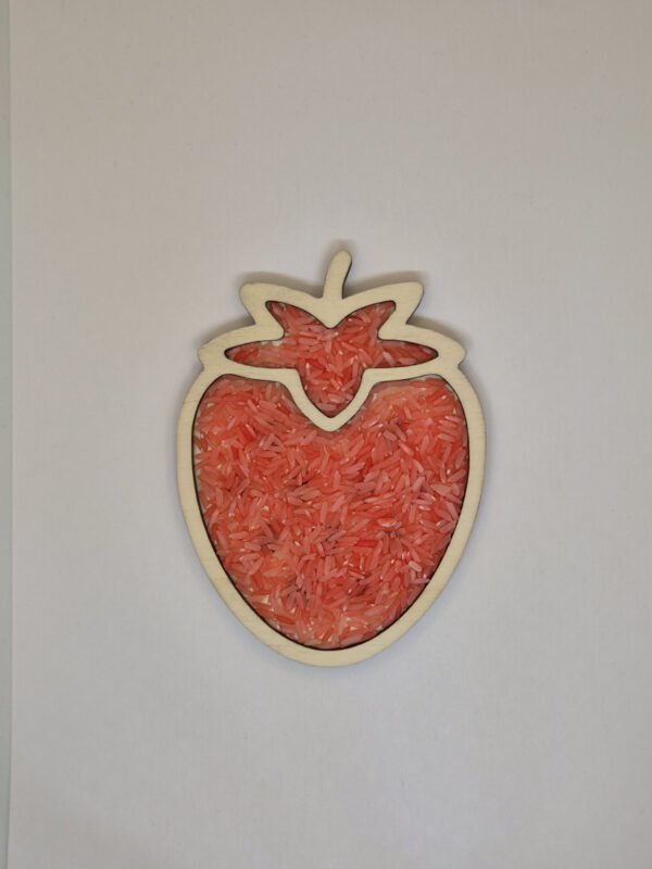 Houten sensorische vulvorm in de vorm van een aardbei gevuld met rode speelrijst, geschikt voor sensorisch spel en fijne motoriek.