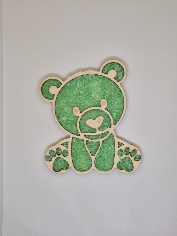 Sensorische vulvorm beer– groene speelrijst Houten sensorische vulvorm in de vorm van een beer gevuld met groene speelrijst, geschikt voor sensorisch spel en fijne motoriek.