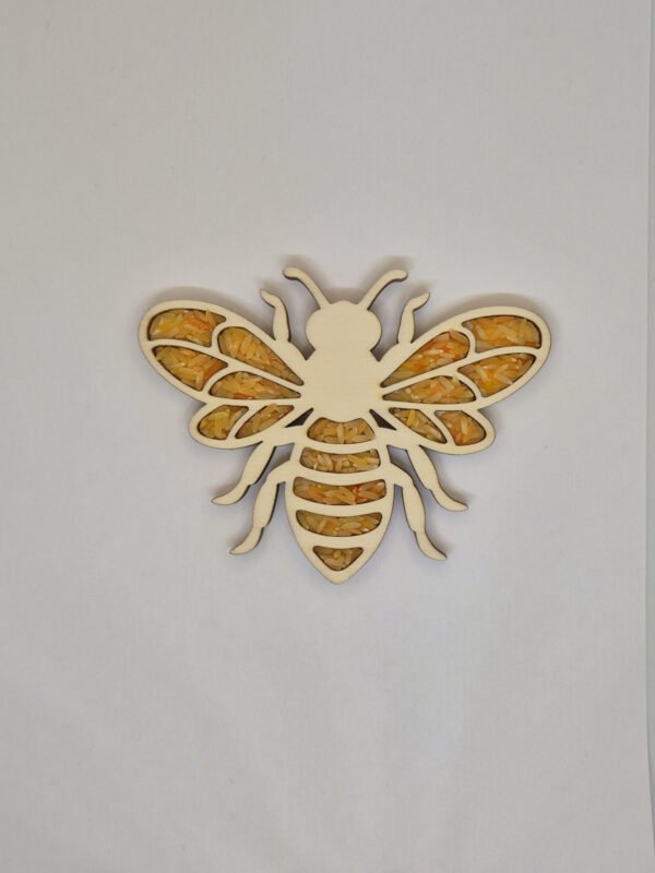 Sensorische vulvorm bij– oranje speelrijst Houten sensorische vulvorm in de vorm van een bij gevuld met oranje speelrijst, geschikt voor sensorisch spel en fijne motoriek.