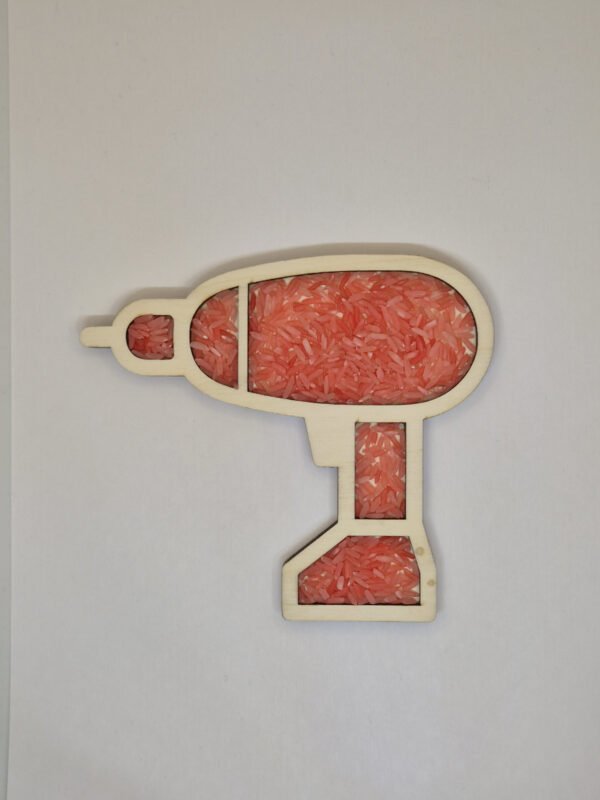 Sensorische vulvorm boormachine– rode speelrijst Houten sensorische vulvorm in de vorm van een boormachine gevuld met rode speelrijst, geschikt voor sensorisch spel en fijne motoriek.