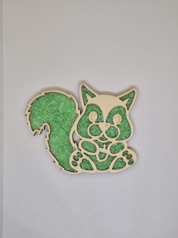 Sensorische vulvorm eekhoorn– groene speelrijst Houten sensorische vulvorm in de vorm van een eekhoorn gevuld met groene speelrijst, geschikt voor sensorisch spel en fijne motoriek.