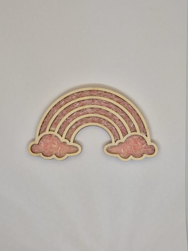 Houten sensorische vulvorm in de vorm van een regenboog gevuld met roze speelrijst, geschikt voor sensorisch spel en fijne motoriek.