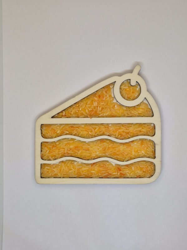 Sensorische vulvorm taart– oranje speelrijst Houten sensorische vulvorm in de vorm van een taart gevuld met oranje speelrijst, geschikt voor sensorisch spel en fijne motoriek.