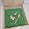 Houten sensorische speelbak gevuld met speelrijst bosmix met houten lepel, dino en dinopootafdruk speelgoed voor kinderen