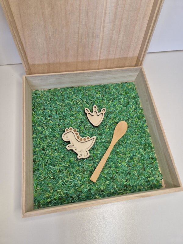 Houten sensorische speelbak gevuld met speelrijst bosmix met houten lepel, dino en dinopootafdruk speelgoed voor kinderen