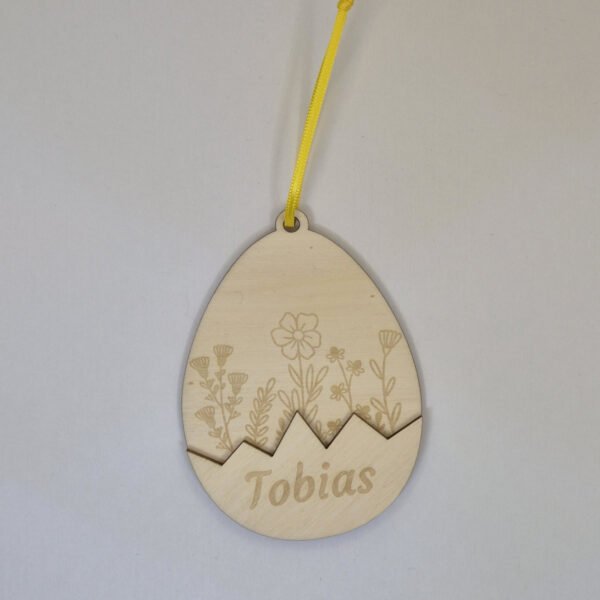 Gepersonaliseerde houten paashanger paasei met naam hangend in een paastak als paasdecoratie in huis