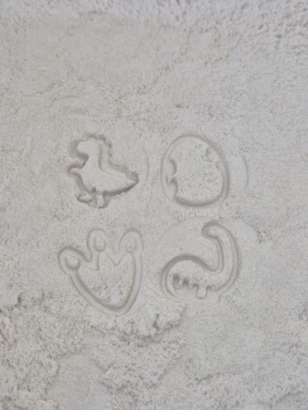 Detail van stempelafdrukken in kinetisch zand gemaakt met houten sensorische stempelset dino voor kinderen