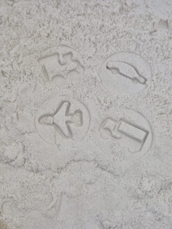 Detail van stempelafdrukken in kinetisch zand gemaakt met houten sensorische stempelset voertuigen voor kinderen